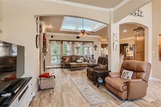 Living room with baseboards, a ceiling fan, crown molding, and light wood-style floors | Image 5