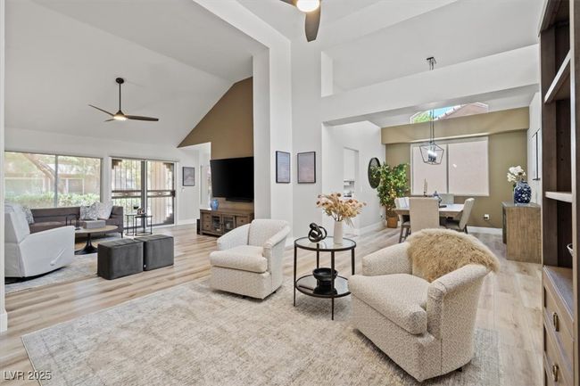 Inside you'll discover soaring majestic ceilings, an open-concept floor plan, sleek pocket windows, & warm natural light. The upgraded interior features luxury flooring, fresh designer paint, & new baseboards. Relax by the linear fireplace or entertain in the formal dining area. | Image 11