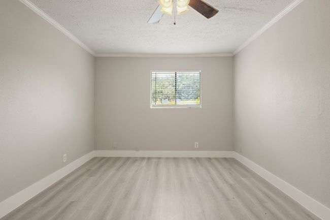 Empty room with a textured ceiling, ornamental molding, light wood finished floors, and a ceiling fan | Image 22