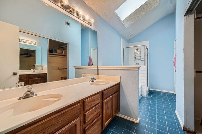 Full bathroom featuring a skylight, lofted ceiling, a shower stall, tile patterned flooring, and a spacious closet | Image 17