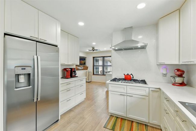 The kitchen features quartz counters with quartz backsplash, recessed lighting and a gas cook top with SS vent hood. | Image 5