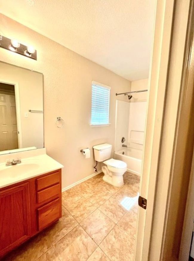 Full bathroom featuring toilet, vanity, tile patterned flooring, a textured ceiling, and shower / bathtub combination | Image 9