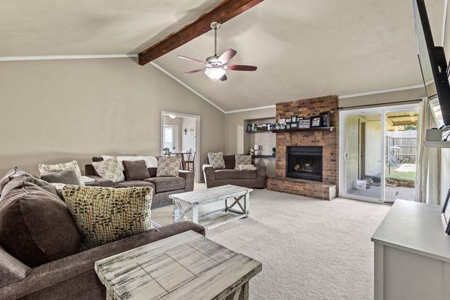 Living area with light colored carpet, plenty of natural light, ceiling fan, a fireplace, and crown molding | Image 10