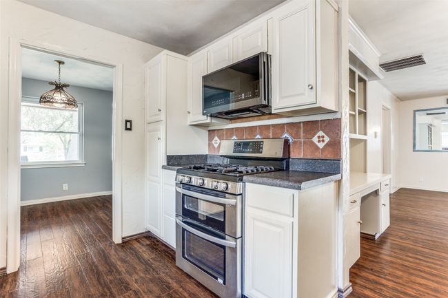 Kitchen with stainless steel appliances, dark wood-style floors, and white cabinetry | Image 15