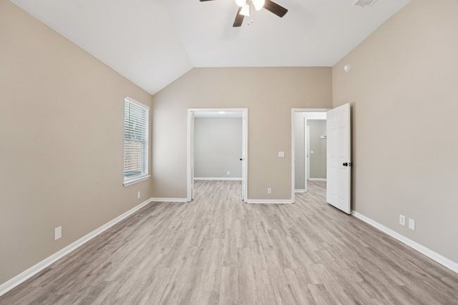 Unfurnished bedroom with lofted ceiling, light wood finished floors, a walk in closet, and a ceiling fan | Image 19