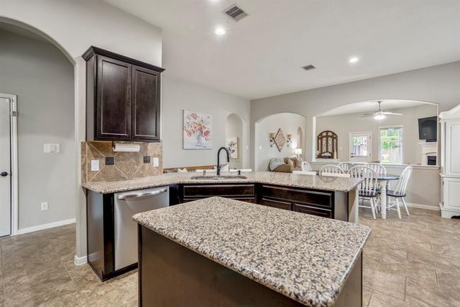 Standing at the island, look out toward the dining area and open living room beyond. The half wall with an arched opening provides gentle separation while keeping the space bright and connected. Also visible is the nearly new dishwasher, installed in 2025. | Image 10