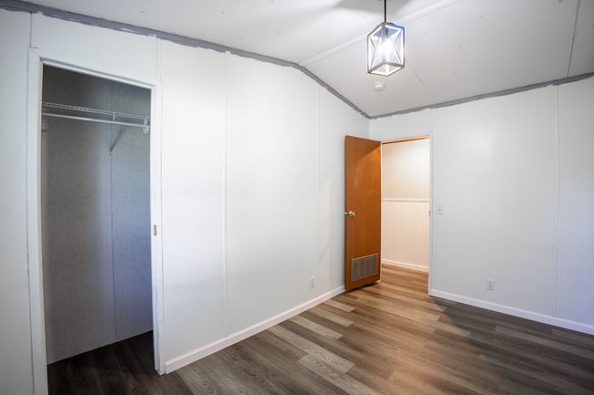 Unfurnished bedroom with wood finished floors, vaulted ceiling, and a closet | Image 27