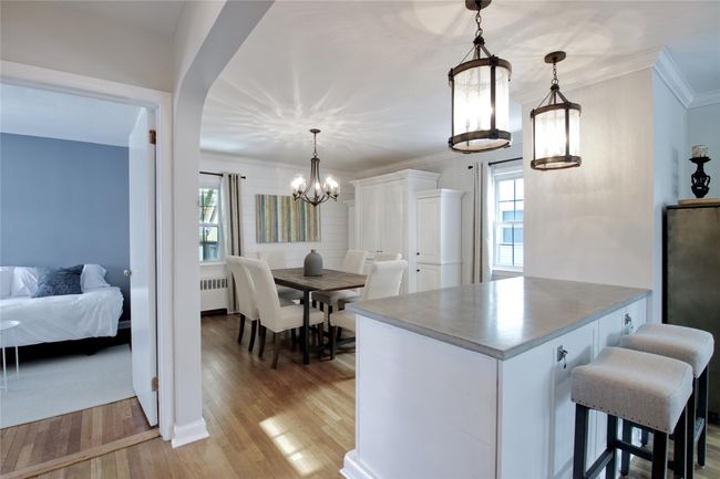 Kitchen with radiator heating unit, a chandelier, light wood-type flooring, ornamental molding, and a breakfast bar | Image 5