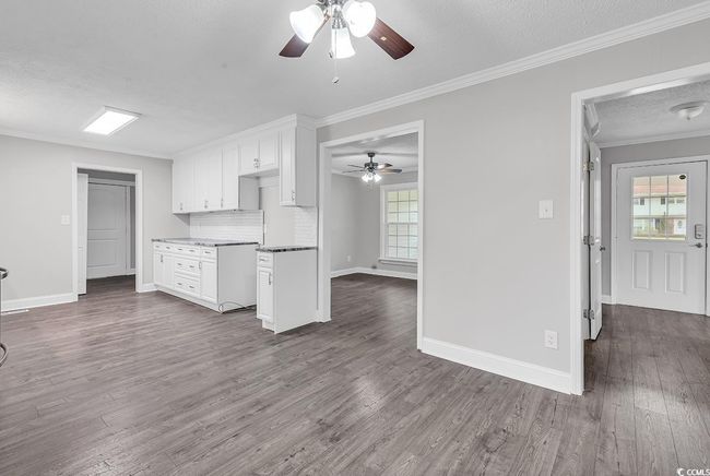 Kitchen with a ceiling fan, crown molding, plenty of natural light, a textured ceiling, and dark wood-type flooring | Image 11