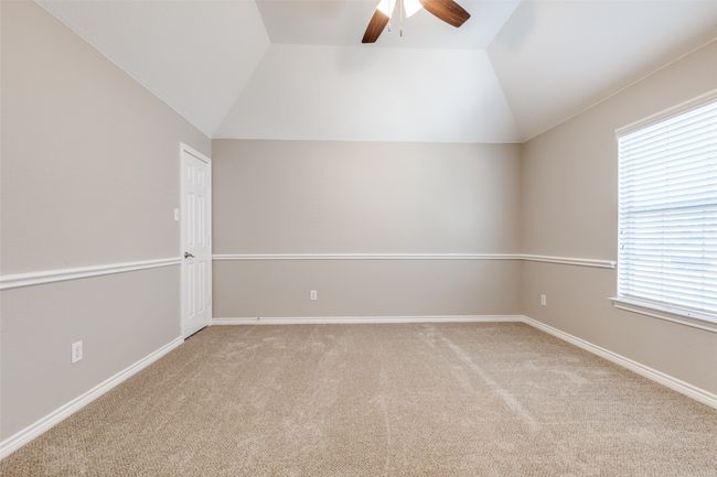 Empty room with baseboards, lofted ceiling, a ceiling fan, and light colored carpet | Image 23