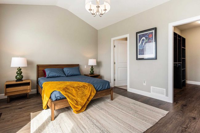 Bedroom with a chandelier, baseboards, vaulted ceiling, and wood finished floors | Image 22