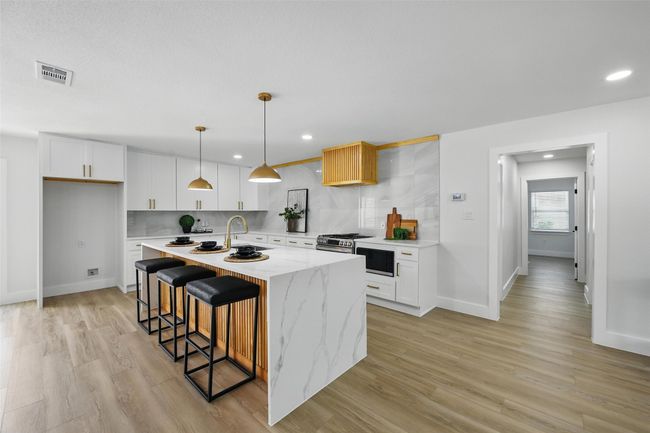 Kitchen with a sink, light wood finished floors, recessed lighting, white cabinetry, and an island with sink | Image 13
