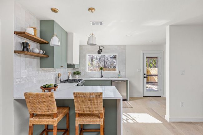 Kitchen featuring appliances with stainless steel finishes, light countertops, backsplash, open shelves, and a peninsula | Image 15