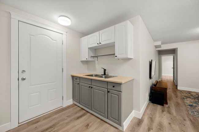 Kitchen featuring light wood finished floors, white cabinetry, a sink, and gray cabinets | Image 26