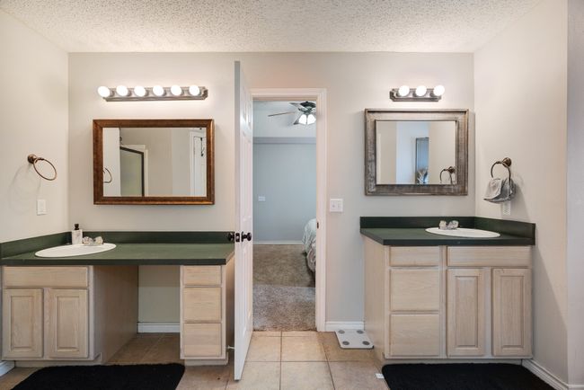 Full bathroom with connected bathroom, two vanities, ceiling fan, a textured ceiling, and tile patterned floors | Image 11