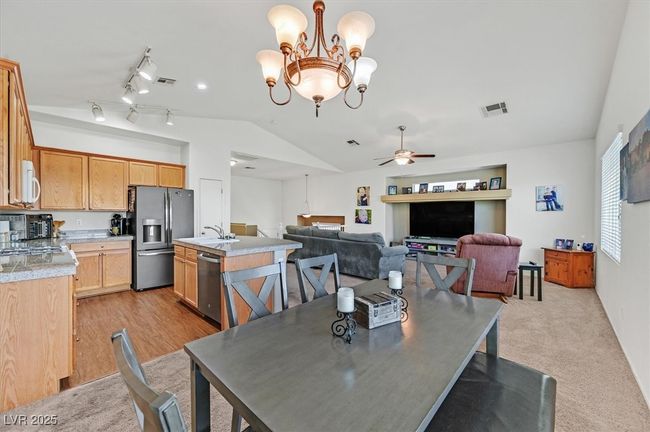 Dining space featuring vaulted ceiling, ceiling fan, and a chandelier | Image 7