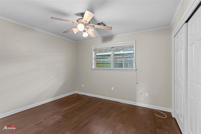 Unfurnished bedroom with dark wood finished floors, ornamental molding, baseboards, a closet, and ceiling fan | Image 11