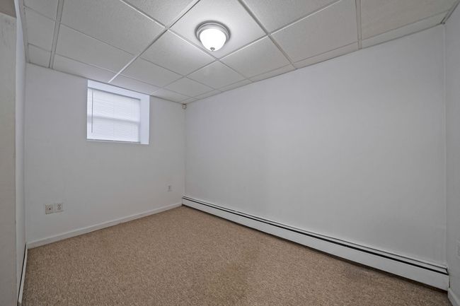 Below grade area featuring carpet, baseboards, a baseboard heating unit, and a paneled ceiling | Image 23