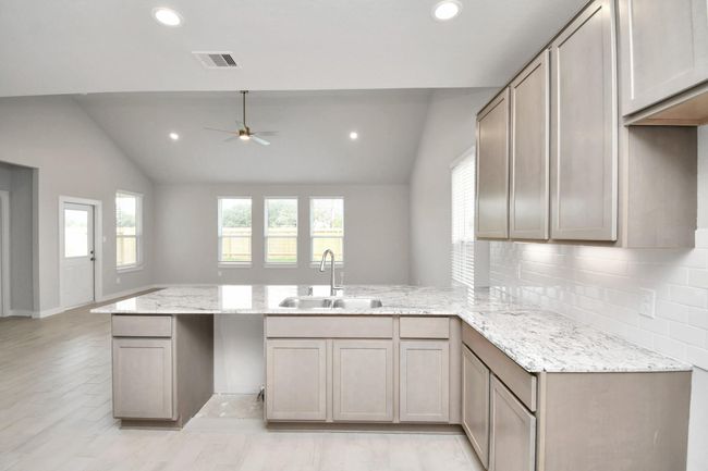The kitchen is a culinary haven, featuring granite countertops, a tile backsplash, stainless steel appliances, 42” upper cabinets, and undercabinet lighting. | Image 14