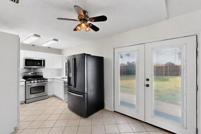 Kitchen with stainless steel appliances, french doors, white cabinetry, a textured ceiling, and healthy amount of natural light | Image 11
