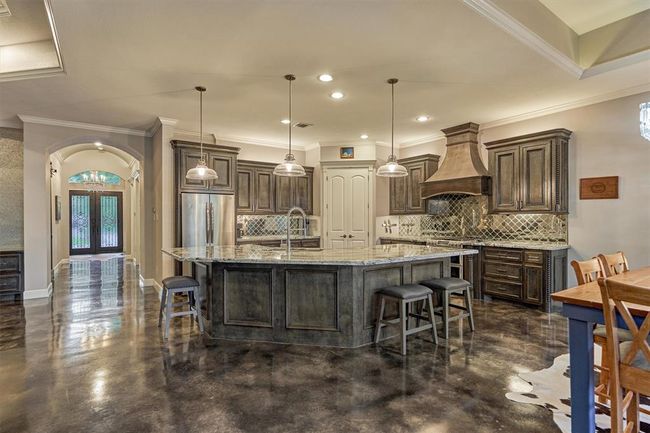 The rich stained cabinetry in the kitchen complements the stained concrete flooring, creating a warm, cohesive look that flows seamlessly throughout the entire home. | Image 21