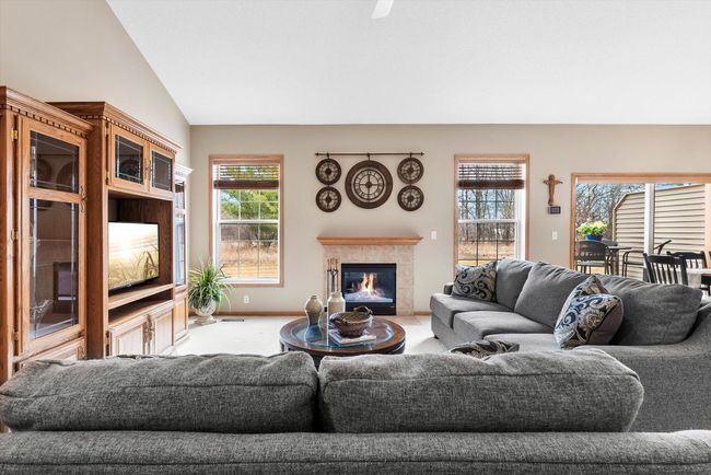 Bright and open living room with vaulted ceilings, ceiling fan, and a spacious layout that flows seamlessly into the dining area and kitchen. | Image 9