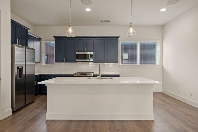 Kitchen featuring stainless steel appliances, light countertops, a sink, tasteful backsplash, and hanging light fixtures | Image 18