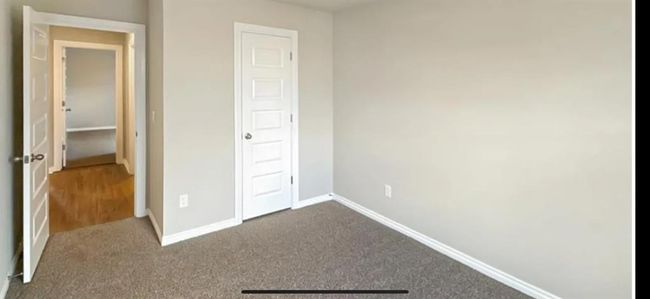 Unfurnished bedroom with dark colored carpet and baseboards | Image 18