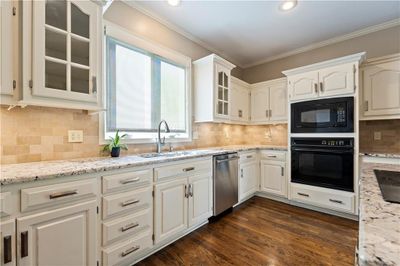 Kitchen featuring black appliances, white cabinetry, dark hardwood flooring, and ornamental molding | Image 2