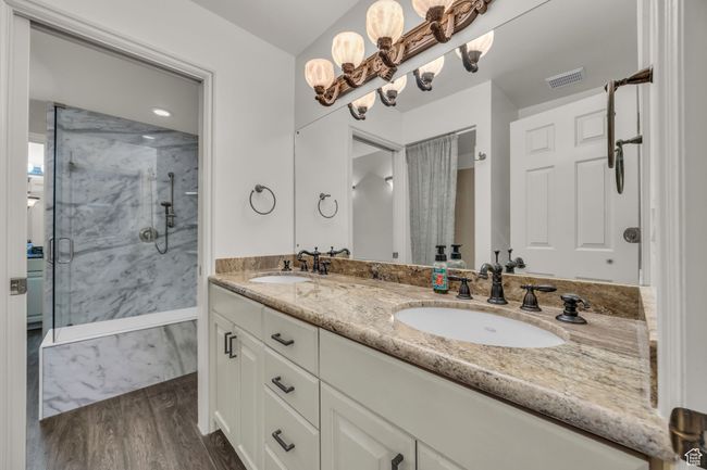 Bathroom featuring a sink, visible vents, a marble finish shower, and wood finished floors | Image 7