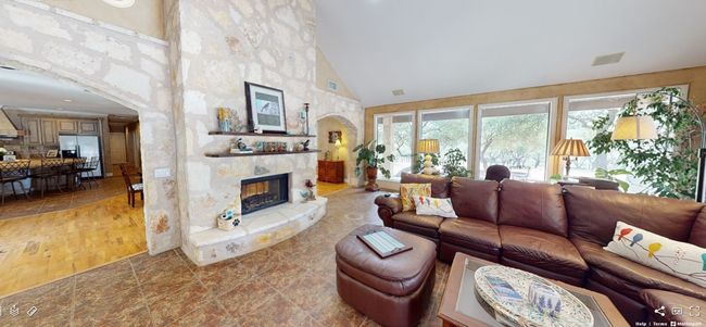 Living room featuring arched walkways, large single pane windows, high vaulted ceiling, and floor-to-ceiling stone see-through fireplace | Image 8