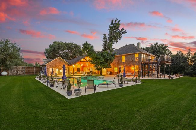 Stunning twilight view of swimming pool with a hot tub, pavillion, pool house, patio areas, and a wooden balcony with stairs | Image 38