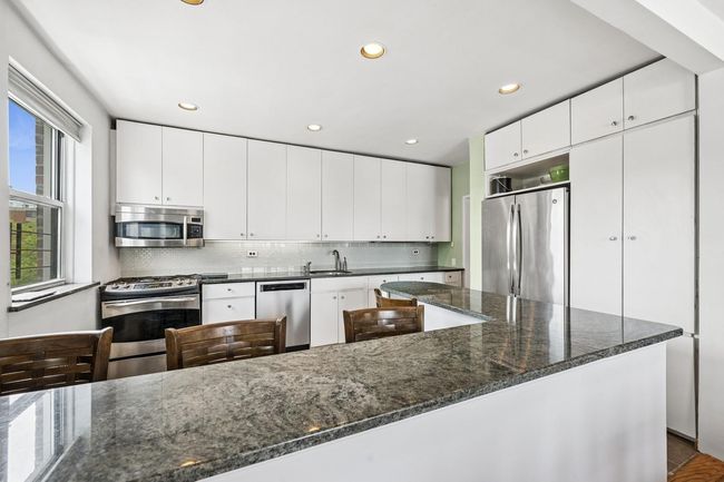 Kitchen with stainless steel appliances, a sink, tasteful backsplash, recessed lighting, and dark stone counters | Image 7