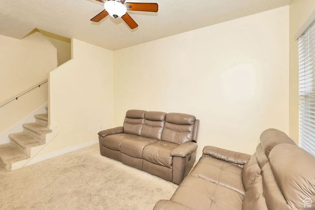 Carpeted living area featuring ceiling fan, stairway, and baseboards | Image 18