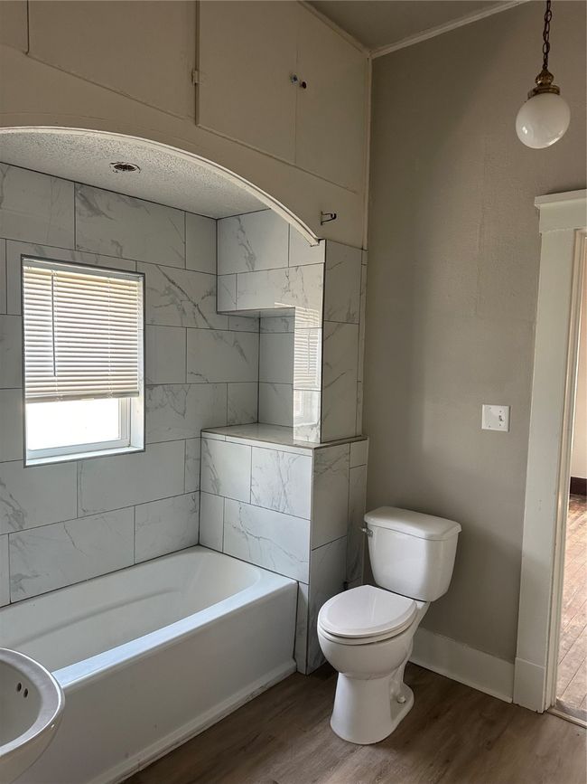 Bathroom with toilet, baseboards, a bathtub, and wood finished floors | Image 9