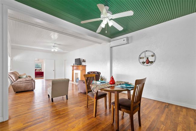 Dining space featuring ceiling fan, a wall mounted AC, wood finished floors, crown molding, and a textured wall | Image 13