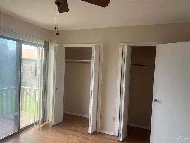 Unfurnished bedroom featuring multiple closets, light wood finished floors, access to exterior, and a ceiling fan | Image 8
