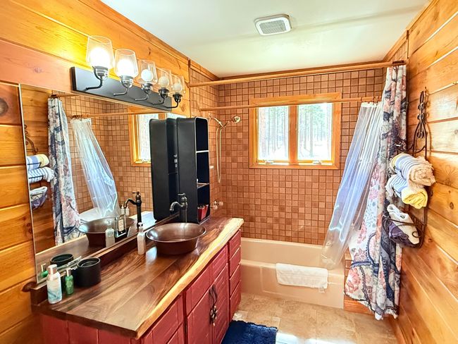 Full bathroom with copper sink vanity, wooden walls, shower / tub combo with curtain | Image 44