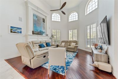 Living room with a healthy amount of sunlight, ornamental molding, dark wood-type flooring, and ceiling fan | Image 1