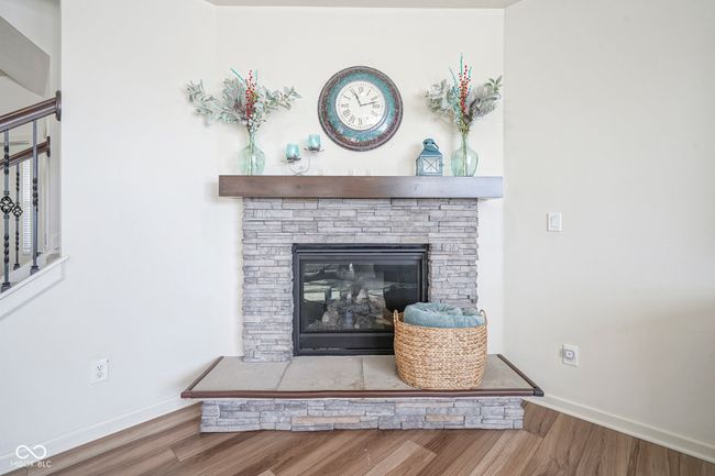 interior details featuring a stone fireplace, baseboards, and wood finished floors | Image 15