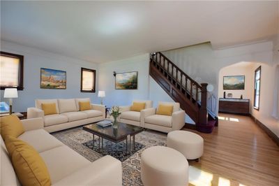 Living room with original wooden staircase and recently refinished floors. VIRTUALLY STAGED | Image 2