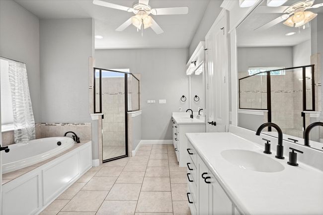 Full bathroom with a ceiling fan, a shower stall, a garden tub, two vanities, and tile patterned floors | Image 21