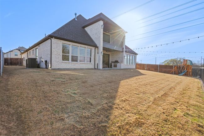 Rear view of house featuring a ceiling fan, a balcony, a playground, and a fenced backyard | Image 31