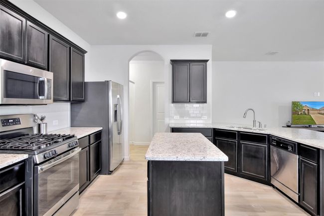 Kitchen with stainless steel appliances, a sink, arched walkways, light wood finished floors, and recessed lighting | Image 6