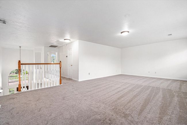 This spacious, game room loft area features neutral tones and ample lighting, with open railing overlooking the floor below, providing a versatile space for many uses. | Image 12