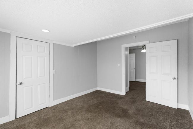 Spare room featuring dark colored carpet and a textured ceiling | Image 10