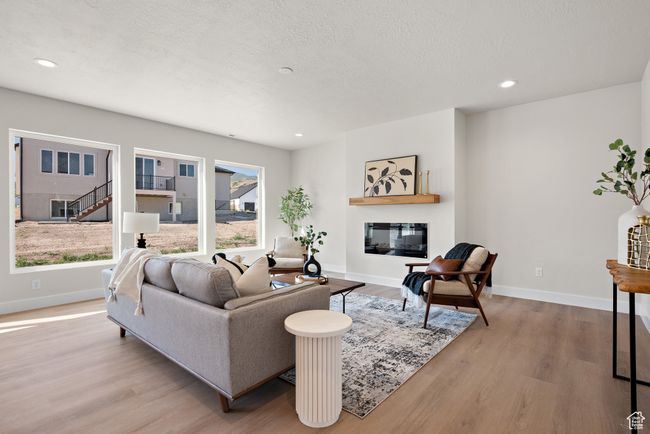 Living area featuring wood finished floors, recessed lighting, a glass covered fireplace, and a textured ceiling | Image 7