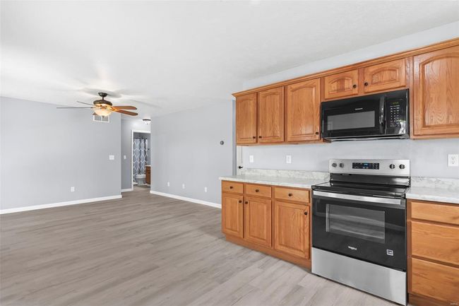 Kitchen featuring a sink, black appliances, a ceiling fan, visible vents, and light countertops | Image 6