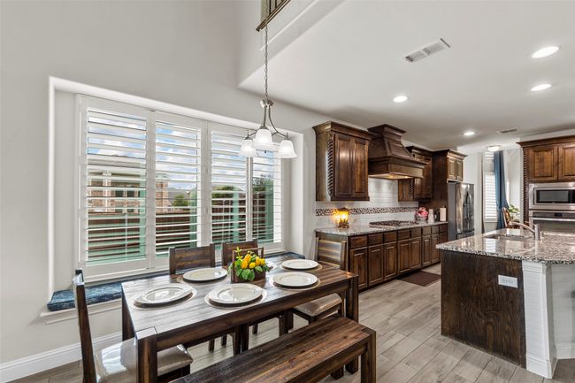 Kitchen featuring stainless steel appliances, wall chimney range hood, hanging light fixtures, a sink, and recessed lighting | Image 14