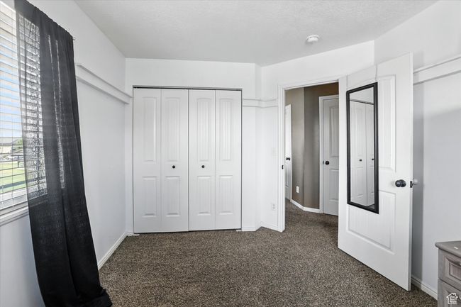 Unfurnished bedroom with dark carpet and a closet | Image 26